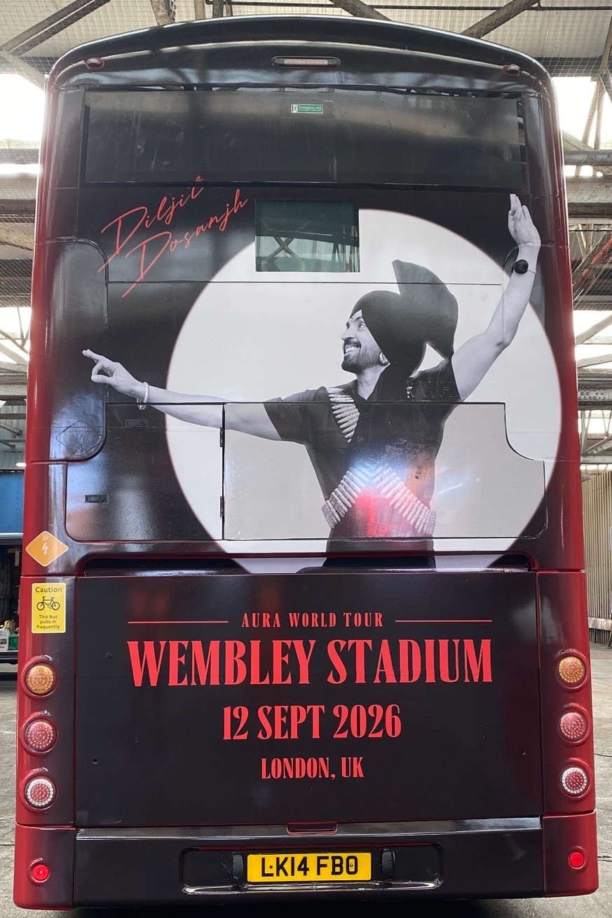 Rear of the wrapped double-decker showing the Aura World Tour creative across both decks
