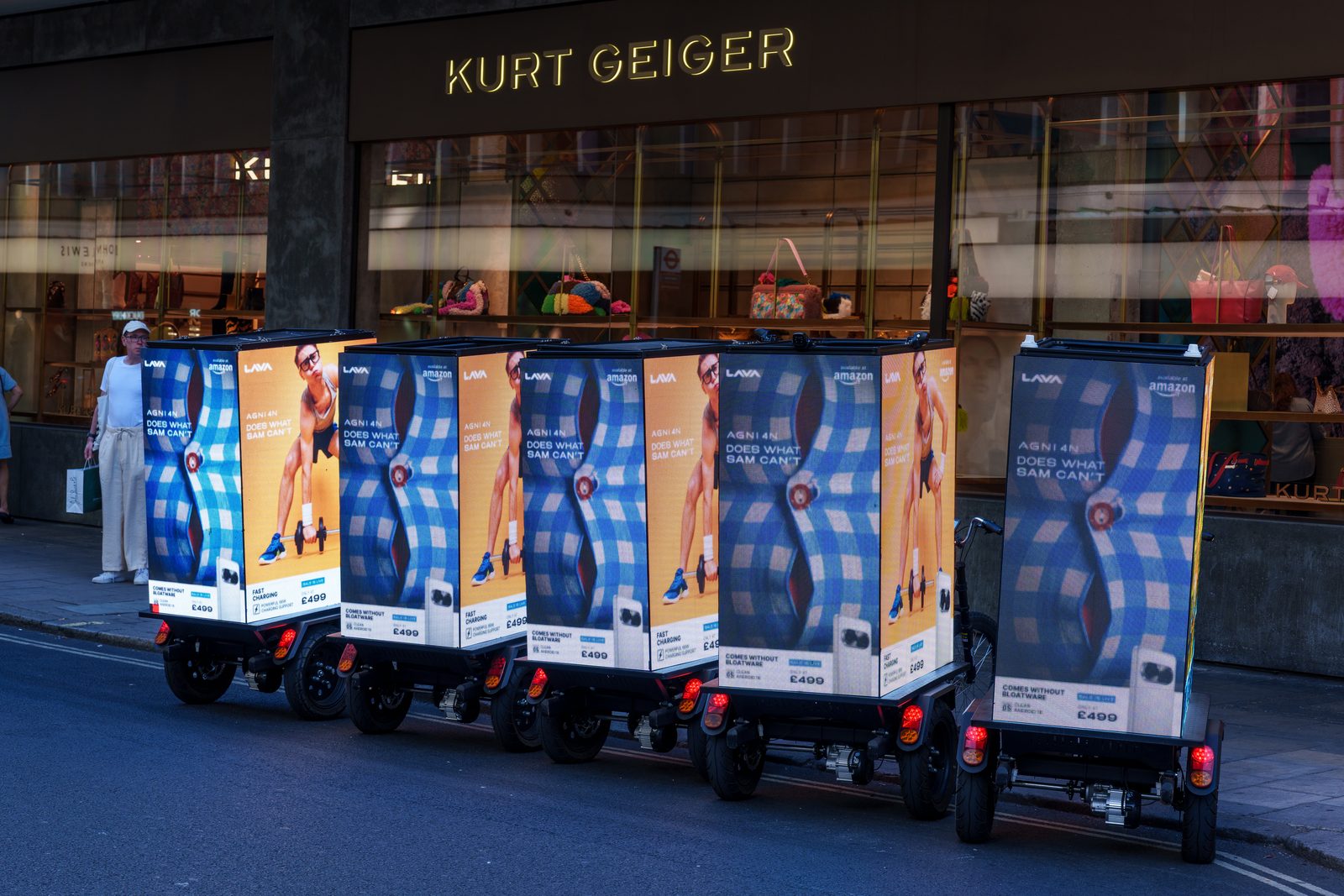 Five digital AdBikes carrying LAVA AGNI 4N artwork lined up outside the shops beside Oxford Street
