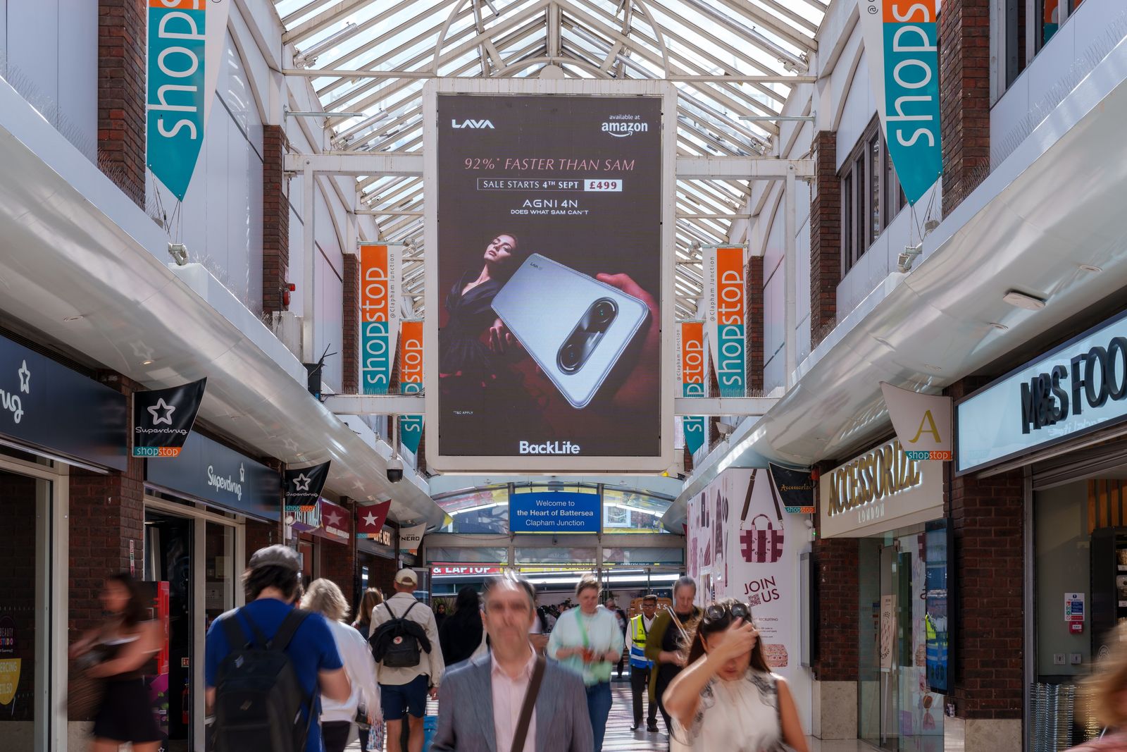 The LAVA AGNI 4N advert on a hanging portrait screen above the crowd in the station arcade at Clapham Junction