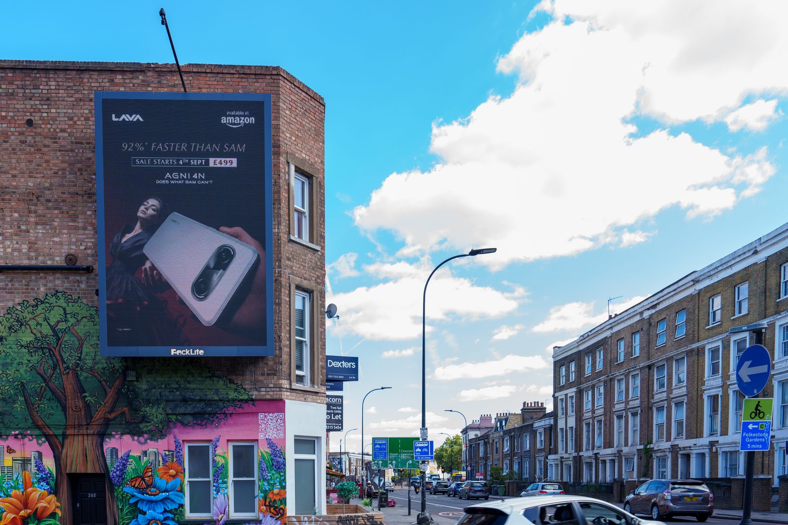 The LAVA AGNI 4N advert on a portrait roadside screen above a painted mural on New Cross Road, London