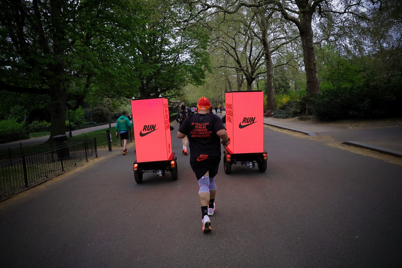 London Marathon runners with a Nike Digital AdBike riding alongside them through a Central London park