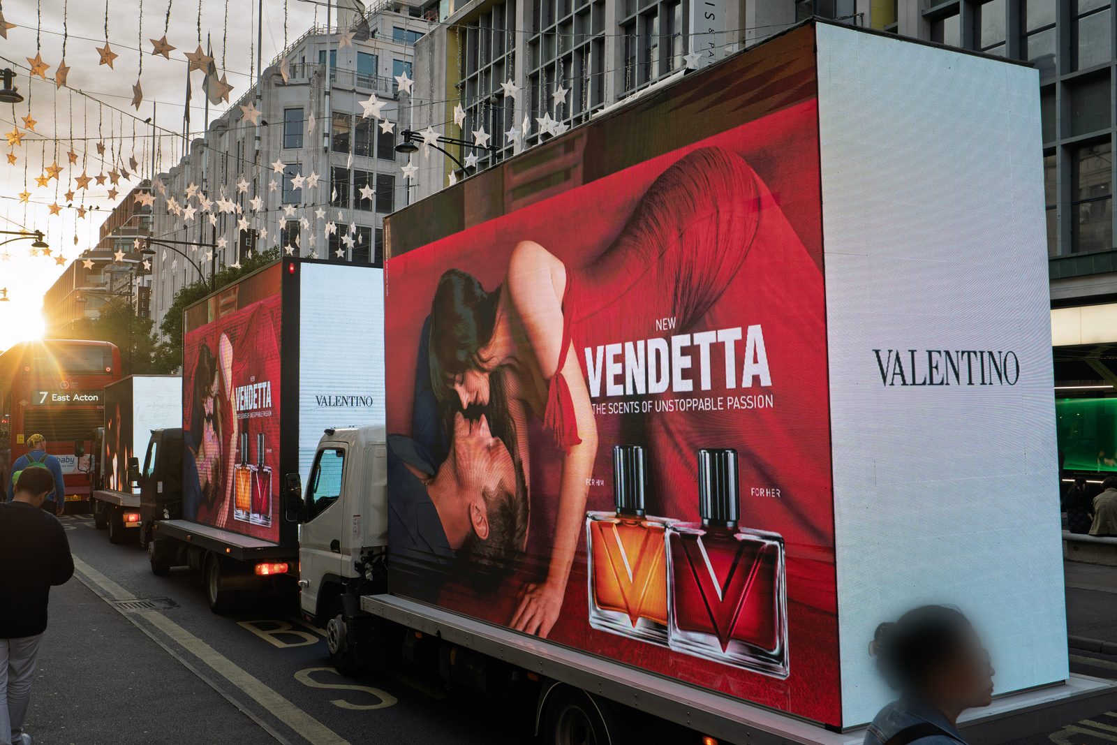 Two Monster AdVans carrying the Valentino Vendetta campaign through Oxford Circus at sunset under the star lights